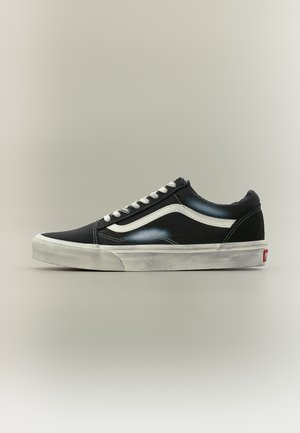 Sneaker nero basso con striscia bianca laterale, lacci bianchi e suola in gomma bianca, mostrato di profilo su uno sfondo neutro.