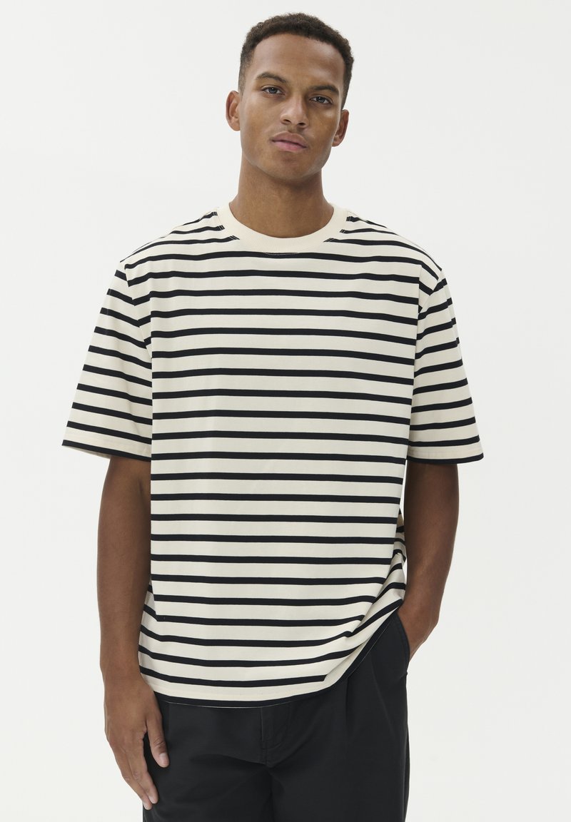 Dryžuotas marškinėlis kreminės ir juodos spalvos iš medvilnės; trumpomis rankovėmis, apvalia kaklo iškirpte, su horizontaliais dryžiais ir laisvu siluetu.