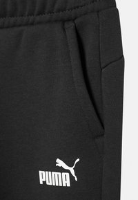 Zwarte sweatpants met een gestructureerde stof, elastische tailleband, zijzakken en een opvallend wit Puma-logo op de dij.