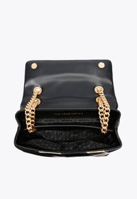 Black leather handbag with gold chain straps, spacious interior featuring a patterned fabric lining and decorative metallic accents.