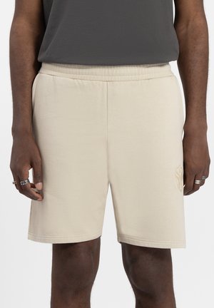 Beige shorts gemaakt van zachte stof, met een elastische tailleband en zijzakken. Geborduurd logo detail op het linkerpootje.