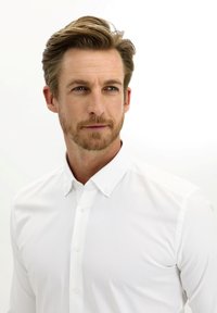 Camicia bianca con bottoni in tessuto liscio, dotata di colletto classico e dettagli con bottoni visibili, posizionata su uno sfondo neutro.