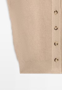Close-up of beige knitted fabric with vertical ribbing and four brown buttons aligned on the right side.