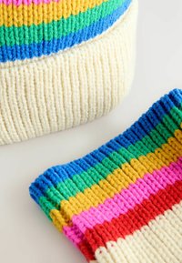 Knitted beanie and wrist warmers in white with multi-colored stripes (pink, yellow, green, blue) featuring textured ribbed design.
