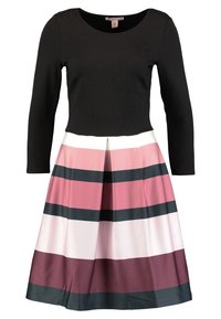 Czarny longsleeve z okrągłym dekoltem, połączony z wielokolorową spódnicą w paski w odcieniach różu, bieli i burgundu.