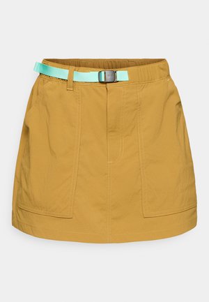 Φούστα κοντή χακί με δύο μπροστινές τσέπες, με αντίθετη τυρκουάζ ζώνη, κατασκευασμένη από ελαφρύ ύφασμα με εμφανείς ραφές.