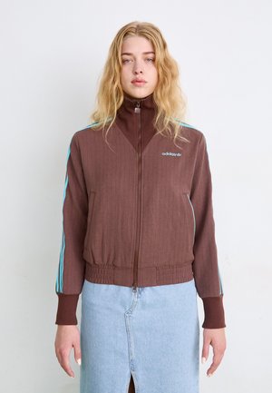 Braune Zip-Jacke mit gerippter Struktur, hohem Kragen und elastischem Saum. Mit kontrastierenden türkisfarbenen Streifen entlang der Ärmel und einem Logodetail.