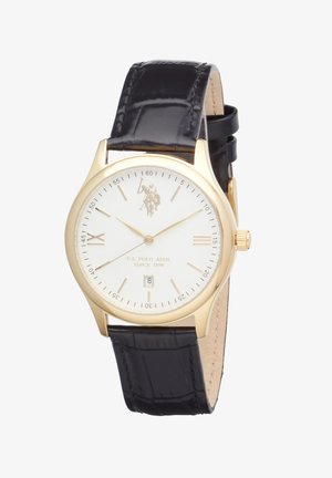 Montre-bracelet analogique ronde ton or avec cadran blanc, bracelet en cuir noir, affichage de la date à 6 heures, et logo U.S. Polo Assn. sur le cadran.
