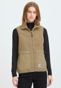 Khakifarbene Fleece-Weste mit hohem Kragen und zwei Fronttaschen; zeichnet sich durch eine weiche Textur und einen Reißverschluss vorne aus. Am unteren Rand beschnitten.