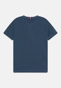 Mørkeblå bomulds t-shirt med korte ærmer, der har en rund halsudskæring og et lille rødt, hvidt og blåt accent på bagsiden af halsen.