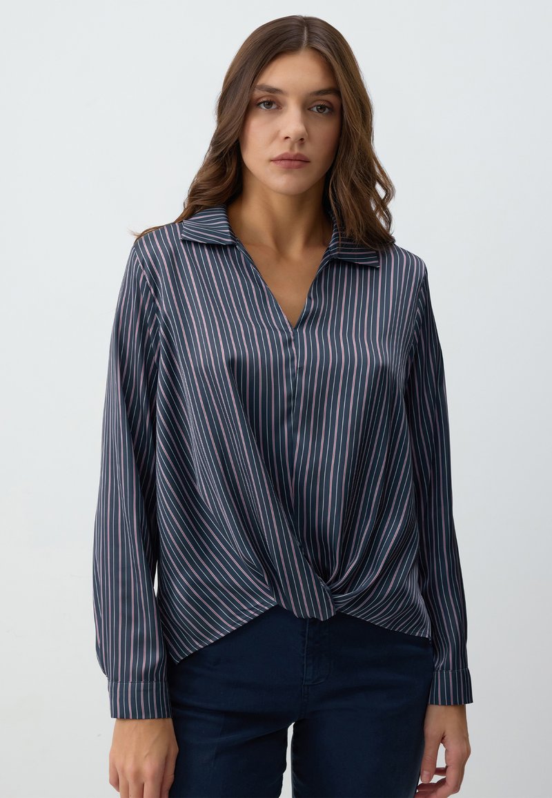 Camicia a maniche lunghe blu navy a righe con colletto e dettaglio annodato sul davanti. Il materiale è liscio con una leggera lucentezza.