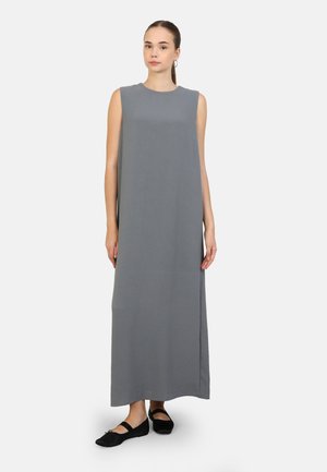 Abito maxi grigio senza maniche con una vestibilità comoda, caratterizzato da un colletto rotondo, fessure laterali e un tessuto leggero e morbido. Scarpe piatte nere indossate.
