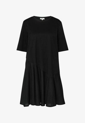 Schwarzes Kleid mit kurzen Ärmeln, rundem Ausschnitt, asymmetrischer Naht in der Taille und ausgestelltem Rock, der über das Knie reicht.