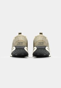 Nike sneakers i olivengrøn med en struktureret mesh-overdel, der har en trækstrop, sort ydersål og en fremtrædende logo på hælen.