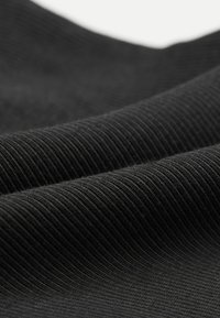 Černá tkanina se vzorem tkaní a žebrovou texturou. Materiál vypadá měkce a mírně elasticky a ukazuje hladké sklady a jemný lesk.