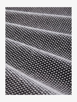 Close-up of black and white textured fabric with small raised dots and wavy folds creating a patterned surface.