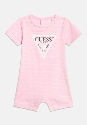 Salopetă roz pentru bebeluși, cu mânecă scurtă, imprimată cu text alb în scris de mână și logo-ul central GUESS USA într-un triunghi alb pe piept.