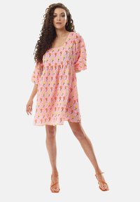 Pink floral dress with puff sleeves, textured fabric, square neckline, and colorful flower pattern. Paired with orange strappy sandals.