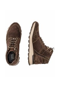 Braune Wildlederstiefel mit einem robusten Design, das strukturierte Oberflächen, kontrastierende Schnürsenkel und eine klobige Sohle mit einem Reißverschlussakzent an der Seite umfasst.