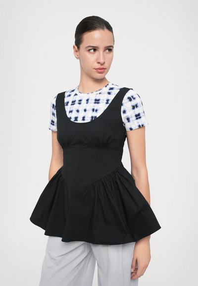 Top peplum negru cu decolteu rotund, țesătură plisată care creează volum, purtat peste o cămașă bleu și albă cu model tie-dye. Textură netedă din bumbac.
