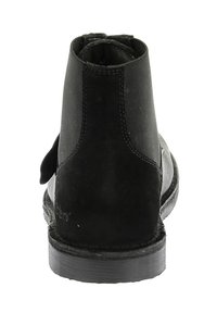Botín de ante negro con un acabado texturizado, paneles laterales elásticos y una suela de goma plana. La parte trasera presenta costuras reforzadas.