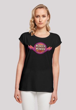 Black cotton t-shirt features a colorful "WONDER WOMAN" graphic with circular design and angular accents in red and pink. Short sleeves.
