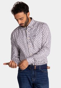 Witte button-up shirt met blauw bladerenpatroon, lange mouwen en traditionele kraag. Draag het met blauwe spijkerbroek en een gevlochten riem.