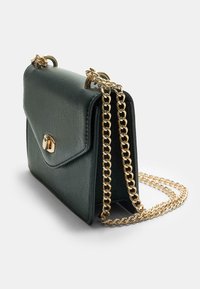 Grüne Lederhandtasche mit einem goldfarbenen Kettenriemen, ausgestattet mit einem Klappverschluss und einer strukturierten Oberfläche. Die Maße sind kompakt und rechteckig.