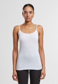 Débardeur blanc avec fines bretelles, en tissu lisse. Doté d'un col rond et d'une coupe ajustée. Style minimaliste sans motifs.