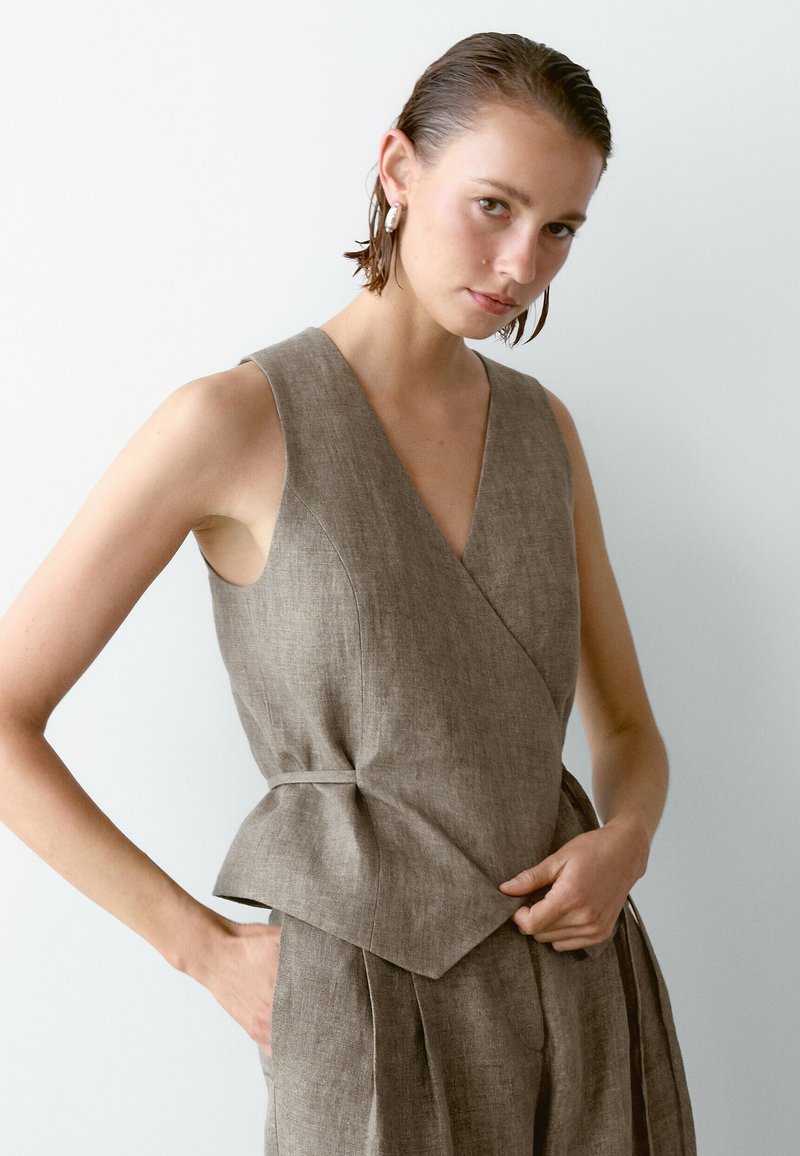 Brązowy lniany top bez rękawów z dekoltem w kształcie litery V i krojem kopertowym; posiada dopasowaną talię, styl peplum oraz gładką fakturę.