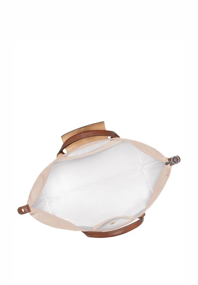Beige fabric bag with a light interior, brown leather accents, a zipper closure, and dual flat handles, designed for easy carrying.