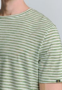 Gestreepte kortekei t-shirt in lichtgroen en wit. Heeft een ronde hals en een klein label met een embleem op de linkermouw. Zachte textuur.