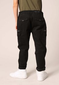 Zwarte cargobroek met meerdere zakken, ritssluitingen en een relaxte pasvorm. Gemaakt van een katoenmix, met knopen en opgerolde manchetten.