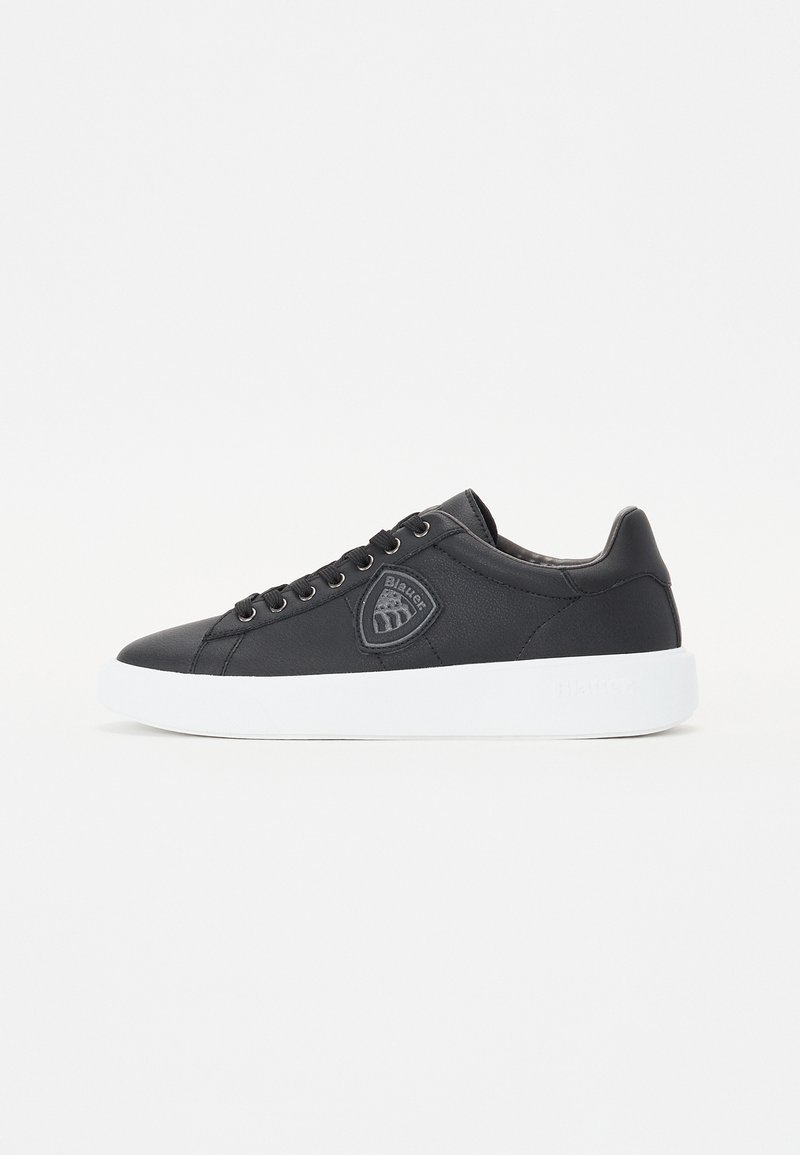 Must musta sneaker, valge kummipohjaga, ümar varvas, nöörimise ees, ja logo šabloon külgedel. Sile tekstuur koos peente õmblustega.