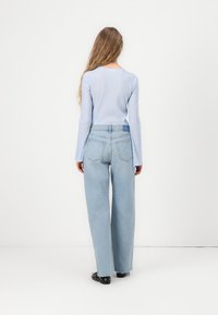 Light blue ribbed long-sleeve top paired with light blue straight-leg jeans featuring a frayed hem and back pockets.