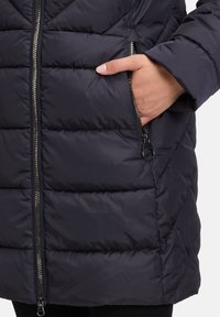 Granatowa puchowa kurtka z pikowanymi elementami, z przodu na zamek błyskawiczny oraz bocznymi kieszeniami na zamek. Wykonana z gładkiego, izolowanego materiału.