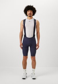 Salopette da ciclismo blu navy con spallacci in rete, dotata di fondello imbottito, tessuto testurizzato e dettagli con logo sugli spallacci. Progettata per comfort e prestazioni.