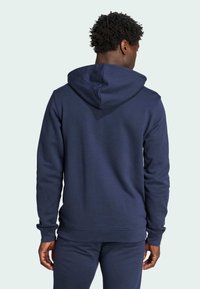 Mörkblå huvtröja av mjukt tyg; har en känguruficka, ribbade mudd och en avslappnad passform med en texturerad yta.