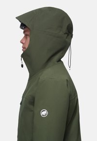 Giacca con cappuccio verde oliva con chiusura a zip, cordoncino regolabile e logo ricamato sulla manica sinistra. Tessuto dal tocco liscio.