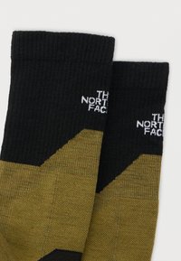 Μαύρες και ελαιί πράσινες κάλτσες crew με ριμπ μανσέτες που φέρουν το λευκό λογότυπο "The North Face" στην πάνω πλευρά.