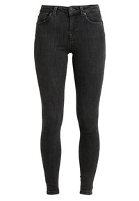 Jeans skinny negros con cierre de botón, bolsillos frontales, pasadores para cinturón y una textura ligeramente deslavada.