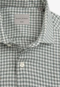 Camicia slim-fit a quadri in bianco e verde. Presenta un colletto a punta e una chiusura con bottoni. Etichetta con la scritta "DAN JOHN." Tessuto morbido e strutturato.