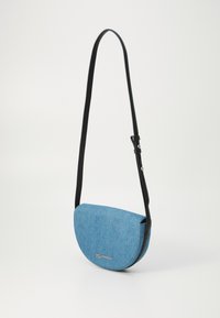 Borsa a tracolla in denim blu con forma arrotondata, tracolla in pelle nera e dettaglio logo in argento sul davanti. Texture liscia, design minimalista.