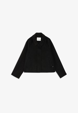Black, cropped jacket with a collared neckline, raglan sleeves, and two front pockets; made from a soft fabric with a smooth texture.