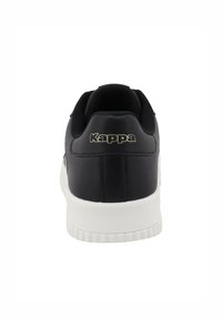 Fekete sportcipő texturált fekete anyaggal, fehér gumitalppal és arany "Kappa" logóval a sarkán. Kerek forma, párnázott boka.