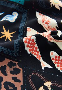 Zwarte stof met kleurrijke patronen: gestileerde vissen, sterren en abstracte vormen in rood, blauw en beige, met een gestructureerd oppervlak.