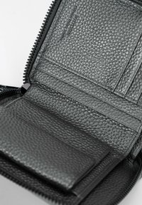 Zwarte leren portemonnee met een textuurafwerking. Beschikt over kaartsleuven, een vak voor biljetten en een ritssluiting voor veilige opberging.