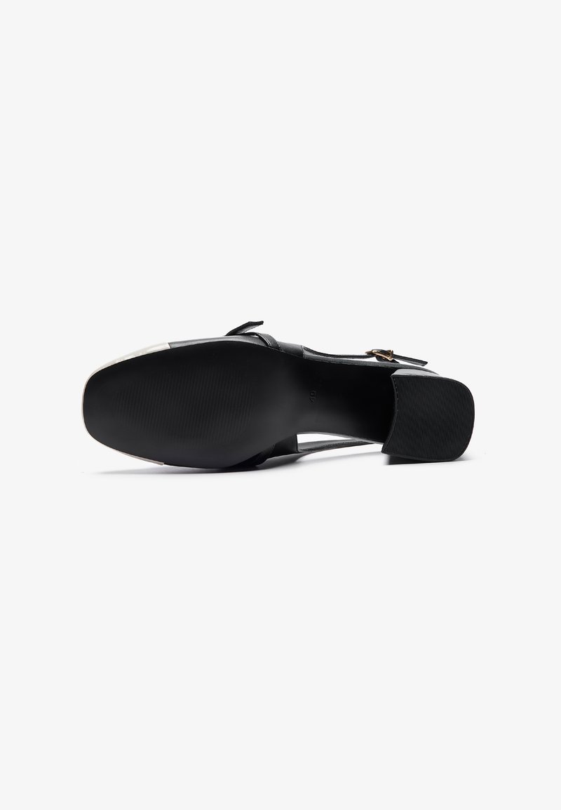 Chaussure en cuir noir avec un talon bloc, présentant une texture lisse, une sangle avec boucle et une semelle en caoutchouc à motif pour une meilleure adhérence.