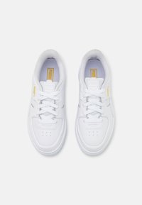 Baskets de sport blanches avec un dessus en cuir lisse, bout rond et détails perforés. Elles disposent de lacets blancs et d'un accent de logo jaune.