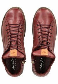 Zapatos de cuero rojo de caña alta con puntera redonda, cierre de cordones y cremalleras laterales. Presentan una superficie texturizada y un acento marrón en la lengüeta.